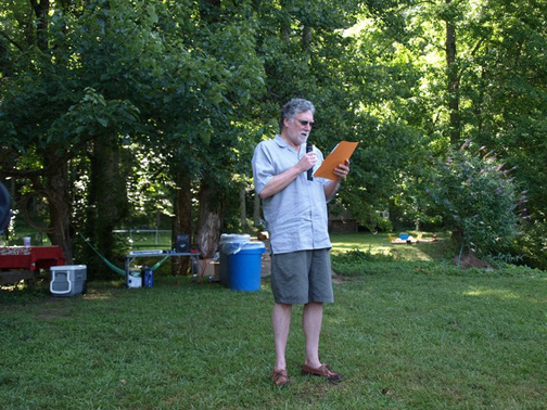 a person standing in the middle of a yard holding a piece of paper