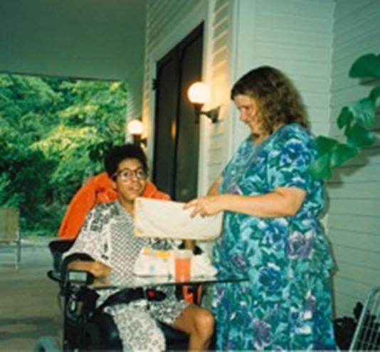 a person in a wheelchair taking to Dottie Adams holding a piece of paper